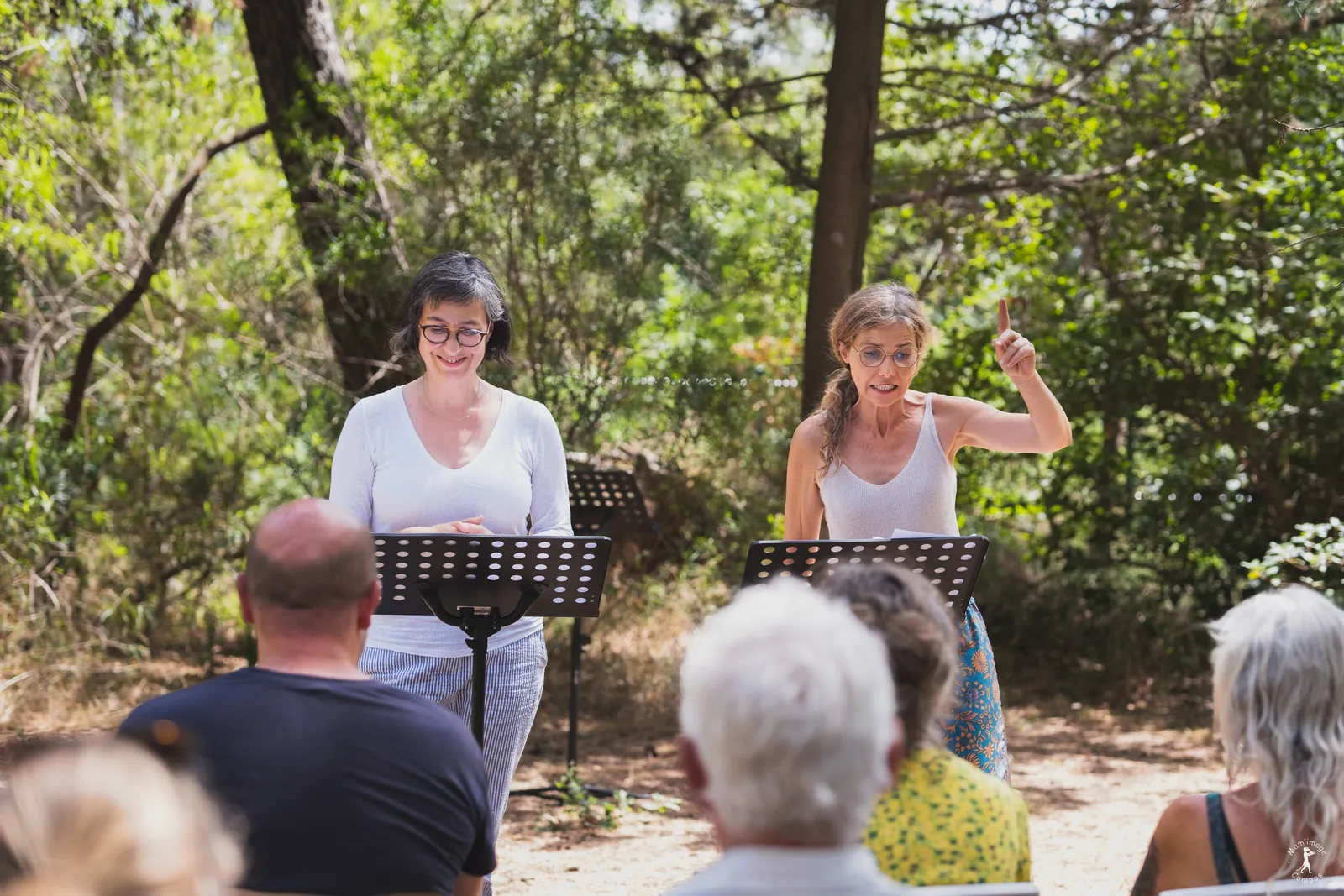 Deux lectrices devant le public dans les jardins du Festival Confluences 2022