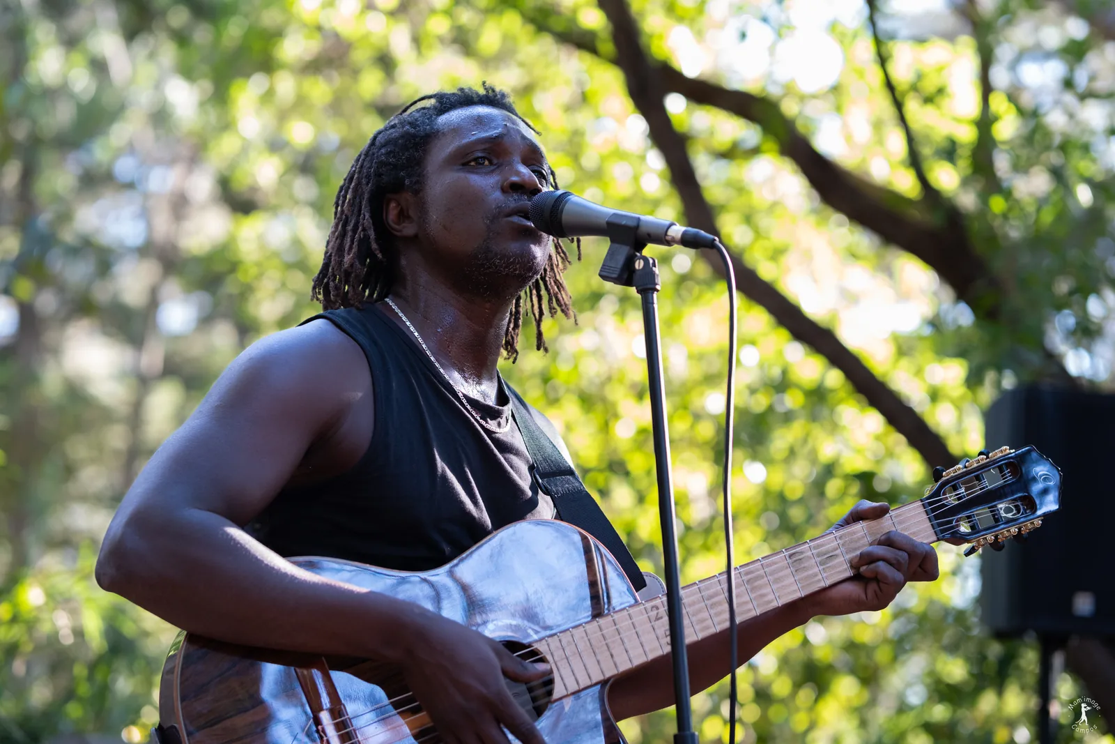 Moussa Diouf chantant et jouant de la guitare pendant le concert afro-folk
