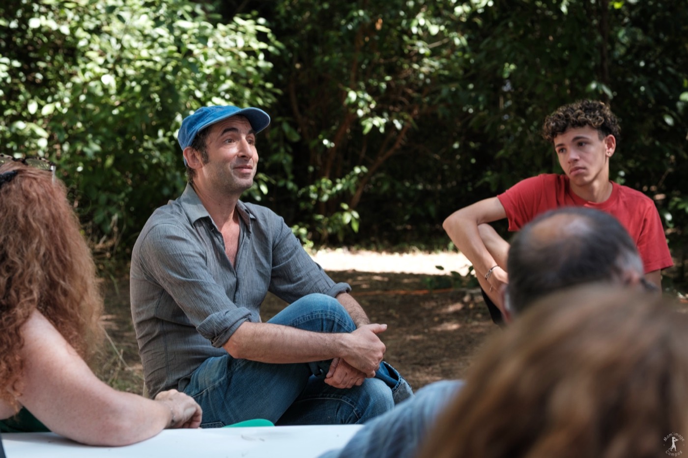 David Lescot échange avec un groupe réuni autour d’une table dans le jardin