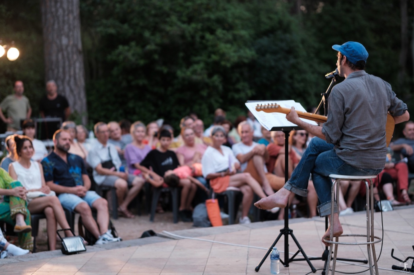 David Lescot joue de la guitare devant un public nombreux installé en plein air