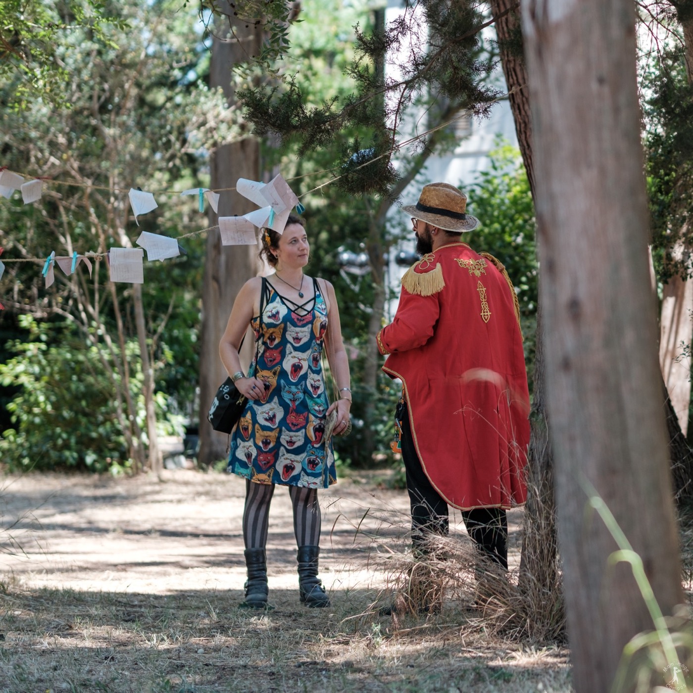 Deux interprètes en costumes colorés jouent entre les arbres du Musée Jean Aicard