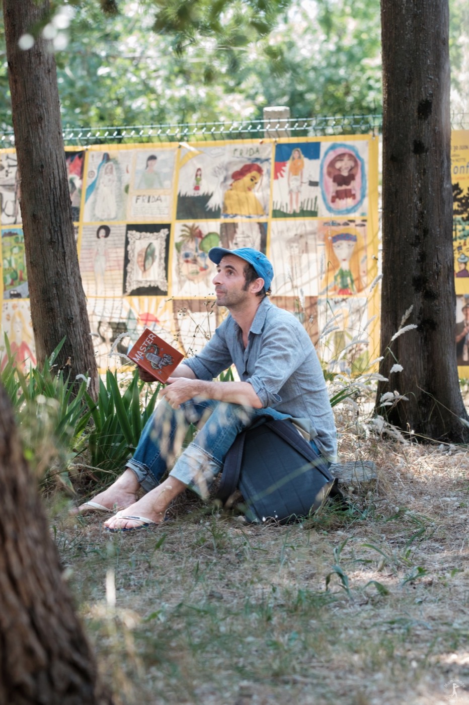 David Lescot assis dans le jardin avec un exemplaire de la pièce Master à la main
